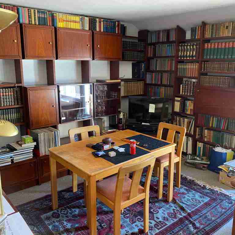 Ein mit vielen Büchern vollgestelltes Wandregal. Ein Tisch steht davor. Eine Wohnungsentrümpelung steht bevor.