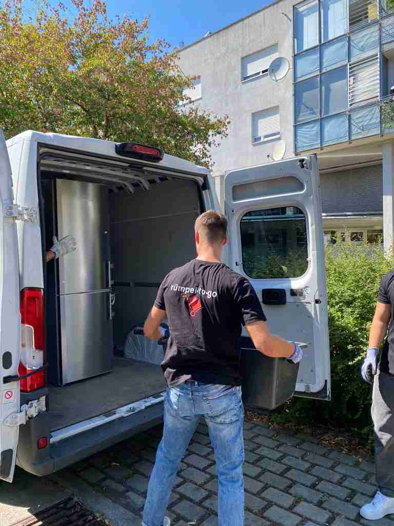 entruempelung bei dem ein Mann einen Kühlschrank in einen Transporter legt