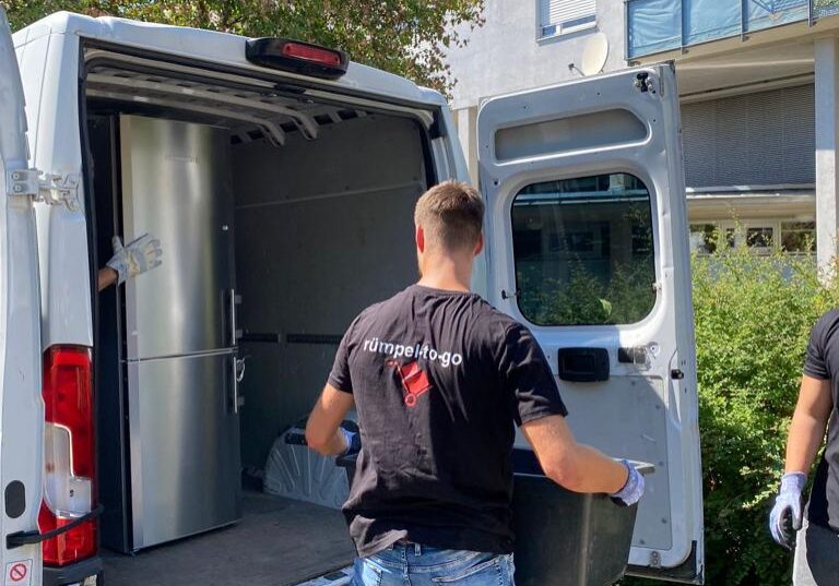entrümpelung und haushaltsauflösung bei dem ein Mann einen Kühlschrank in einen Transporter legt